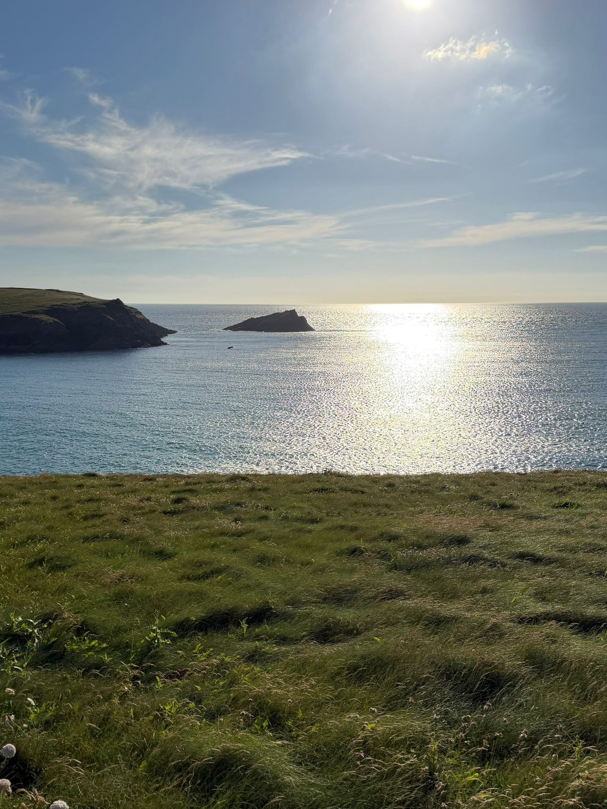 Sunlit bay with island, Cornwall coastline